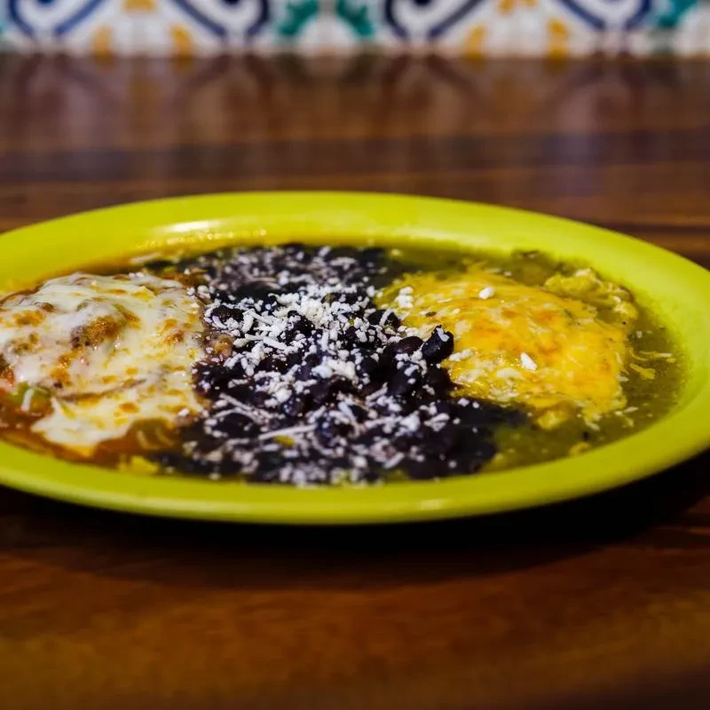 Close-up of a Mexican-style dish with beans, melted cheese, and sauce.