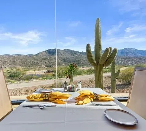 Table for two with yellow napkins overlooks a Saguaro desert.