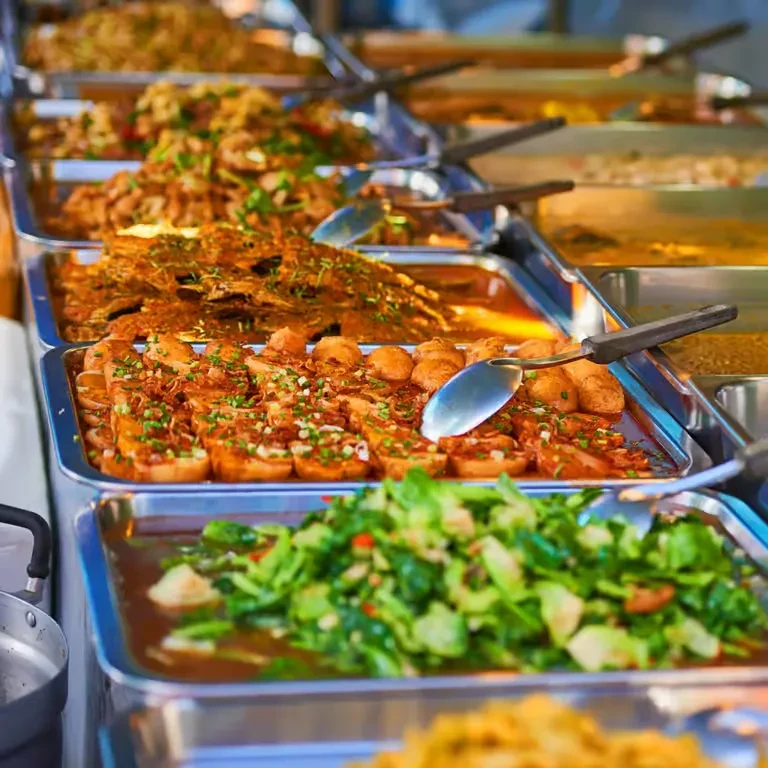 Close-up of Asian buffet trays featuring fried items and green vegetables.