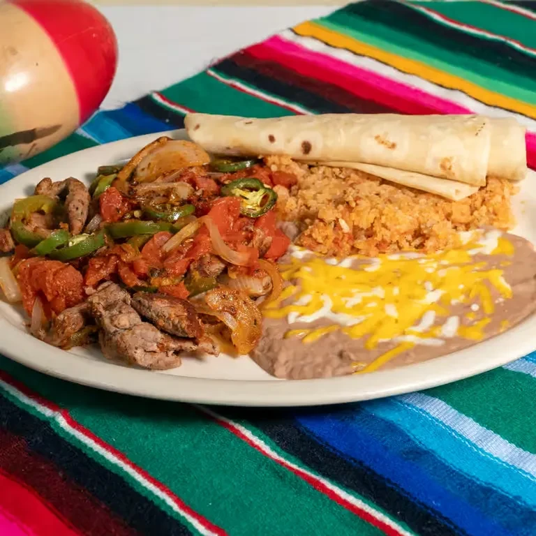 Vibrant Mexican plate with meat, rice, beans, tortillas on serape.