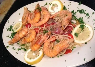 Seafood pasta with whole shrimp, cherry tomatoes, parsley, and lemon slices.