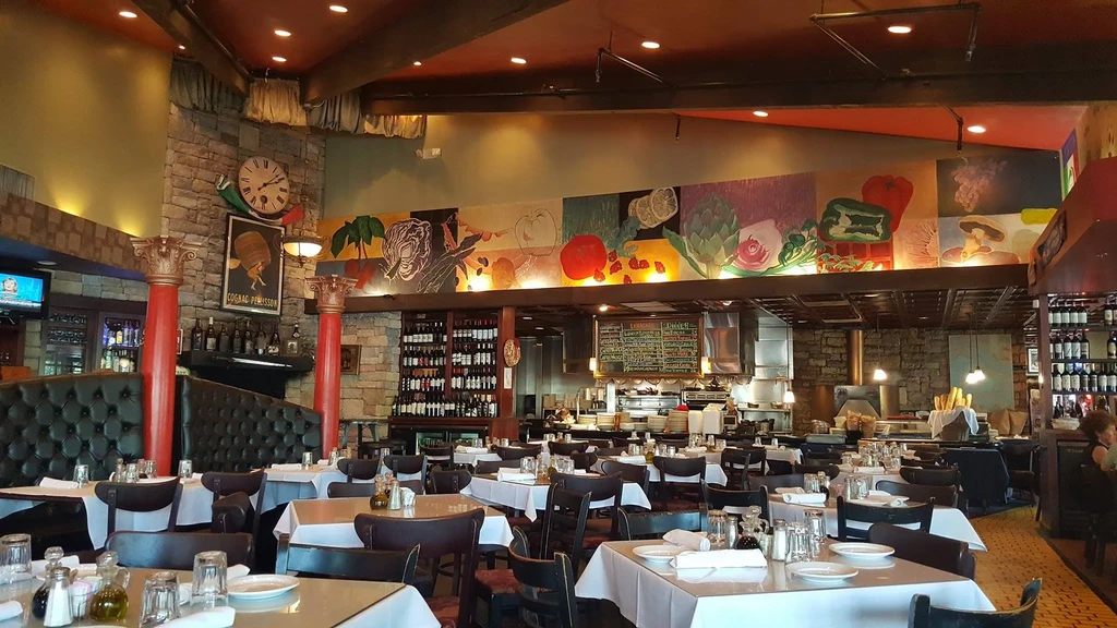 Rustic elegant restaurant interior with colorful mural, dark booths, open kitchen.