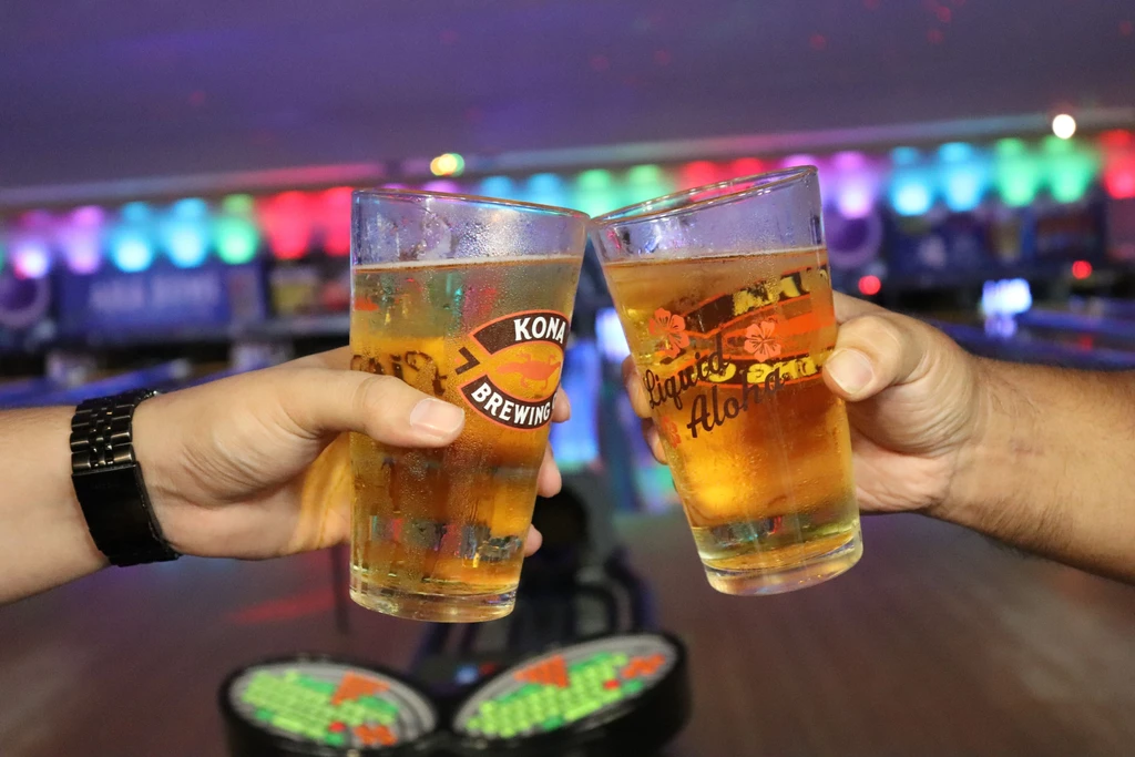 Hands clinking cold beer glasses featuring Kona Brewing and Liquid Aloha.