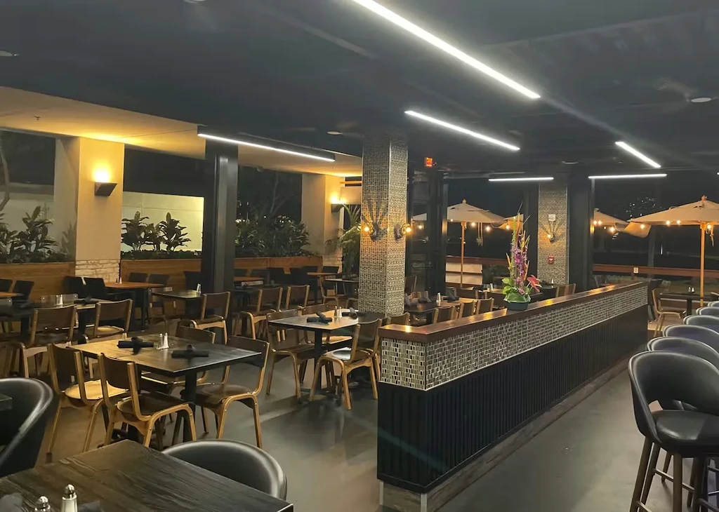 Empty modern restaurant interior at night, showing tables and patio.