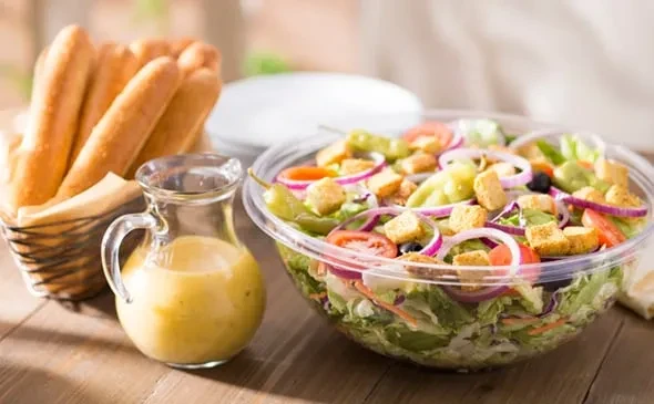 Fresh mixed green salad, toppings, creamy dressing, and breadsticks.