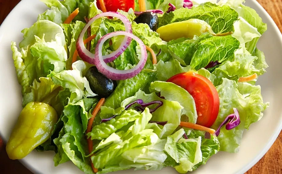 Garden salad with lettuce, tomatoes, olives, onions, carrots, and pepperoncini.