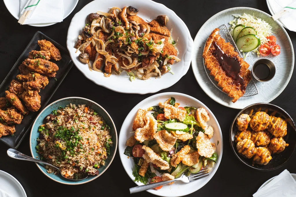 Flat-lay shot: six varied food dishes on a dark tabletop.