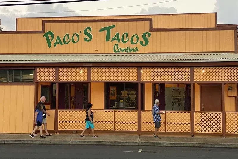 Paco's Tacos Cantina exterior, orange-yellow, with people on sidewalk.