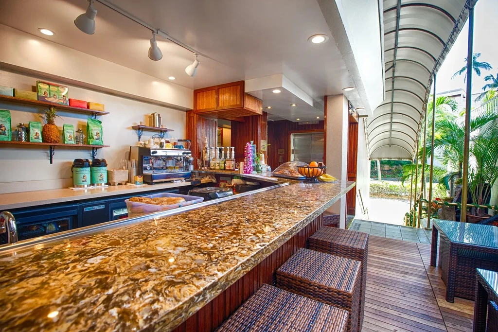 Well-lit cafe bar with granite counter opens to tropical outdoor patio.
