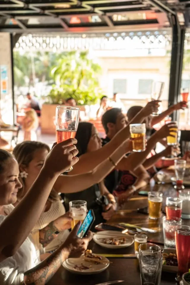 Group of friends toasting drinks outdoors at a restaurant.