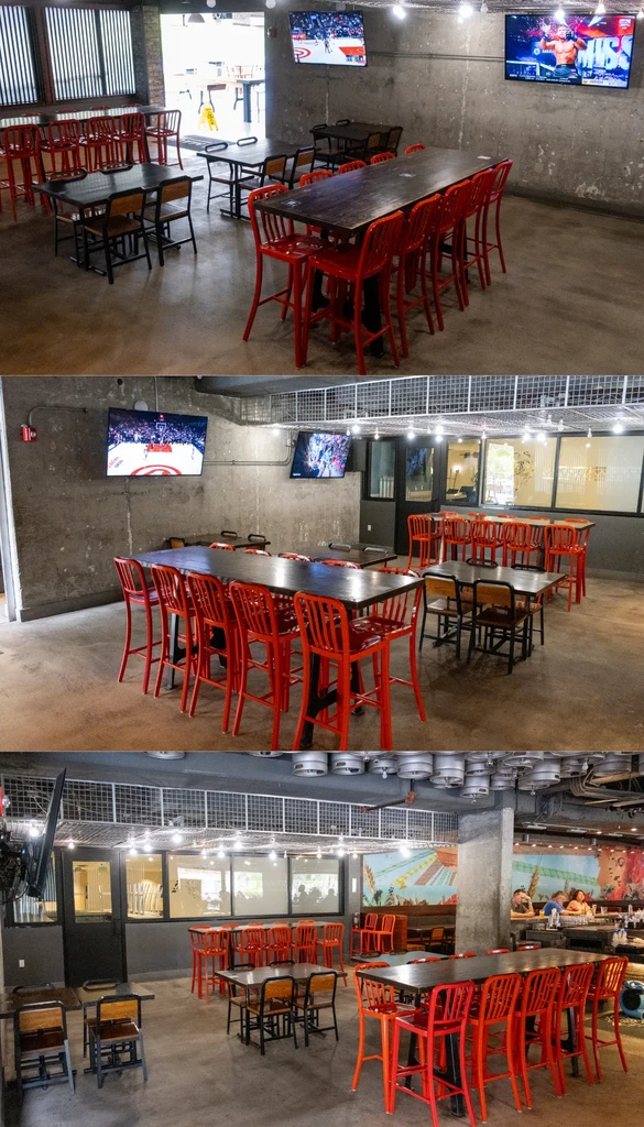 Industrial restaurant interior: concrete walls, red chairs, sports TVs, and bar.