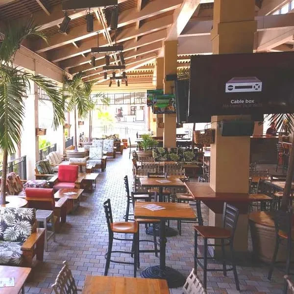 Spacious open-air restaurant/bar with lounge seating and tropical palms.