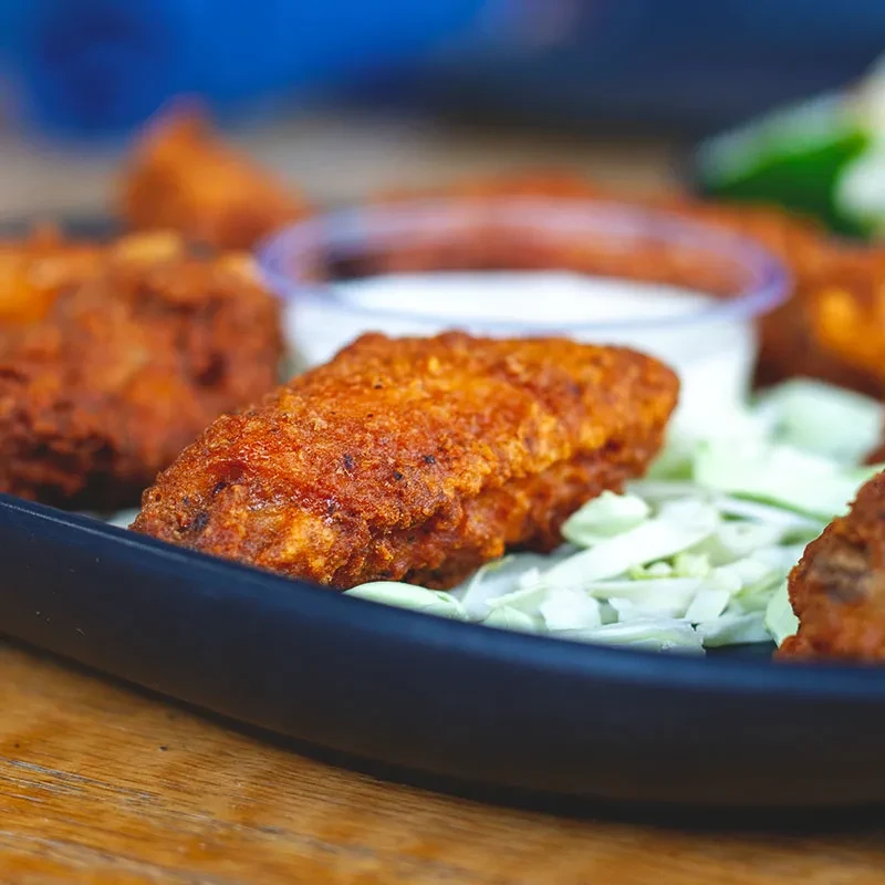 Close-up: crispy fried chicken pieces, shredded cabbage, dipping sauce.