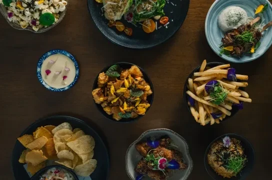 Overhead shot of a wooden table with diverse, artfully presented dishes.