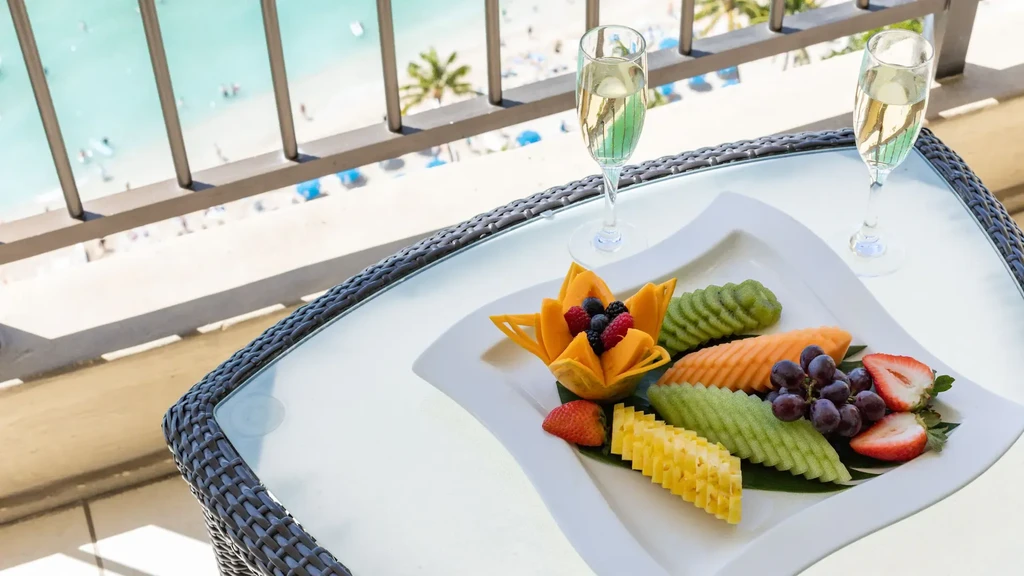 Fruit platter, two glasses, on table overlooking beach and ocean.