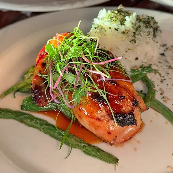 Amber glazed protein, microgreens, string beans, rice, and sauce.