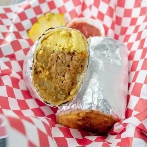 Cut breakfast burrito showing eggs, ground meat, and potatoes in foil.