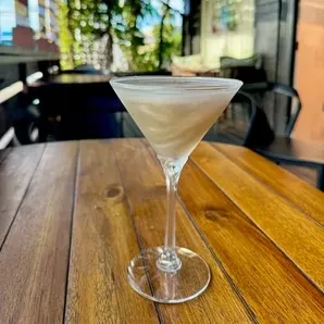 Iridescent cocktail in a martini glass on a rustic outdoor table.