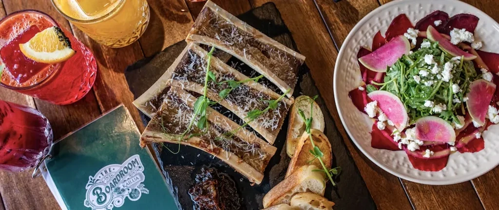 Assortment of bone marrow, salad, cocktails, and "The Boardroom" menu.