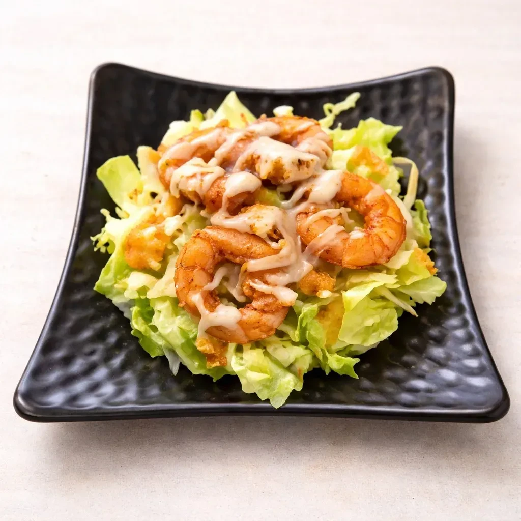 Close-up of shrimp salad with creamy sauce on black plate.