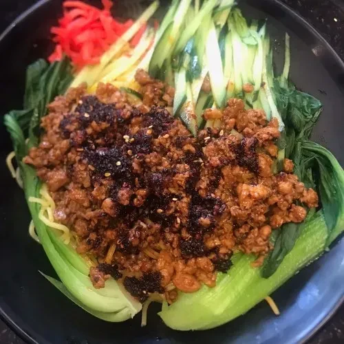 Noodle dish with minced meat, bok choy, cucumber, and pickled ginger.