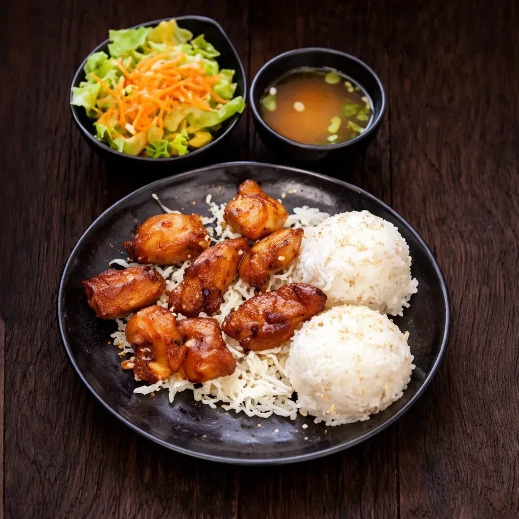 Overhead: Brown-glazed chicken, noodles, rice, salad, and soup on dark wood.