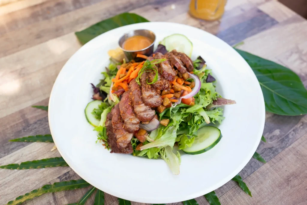 Vibrant salad with seared meat, mixed greens, and creamy dressing.