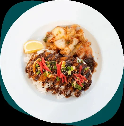 Fried chicken rice bowl, dark sauce, red ginger, kimchi, and lemon.