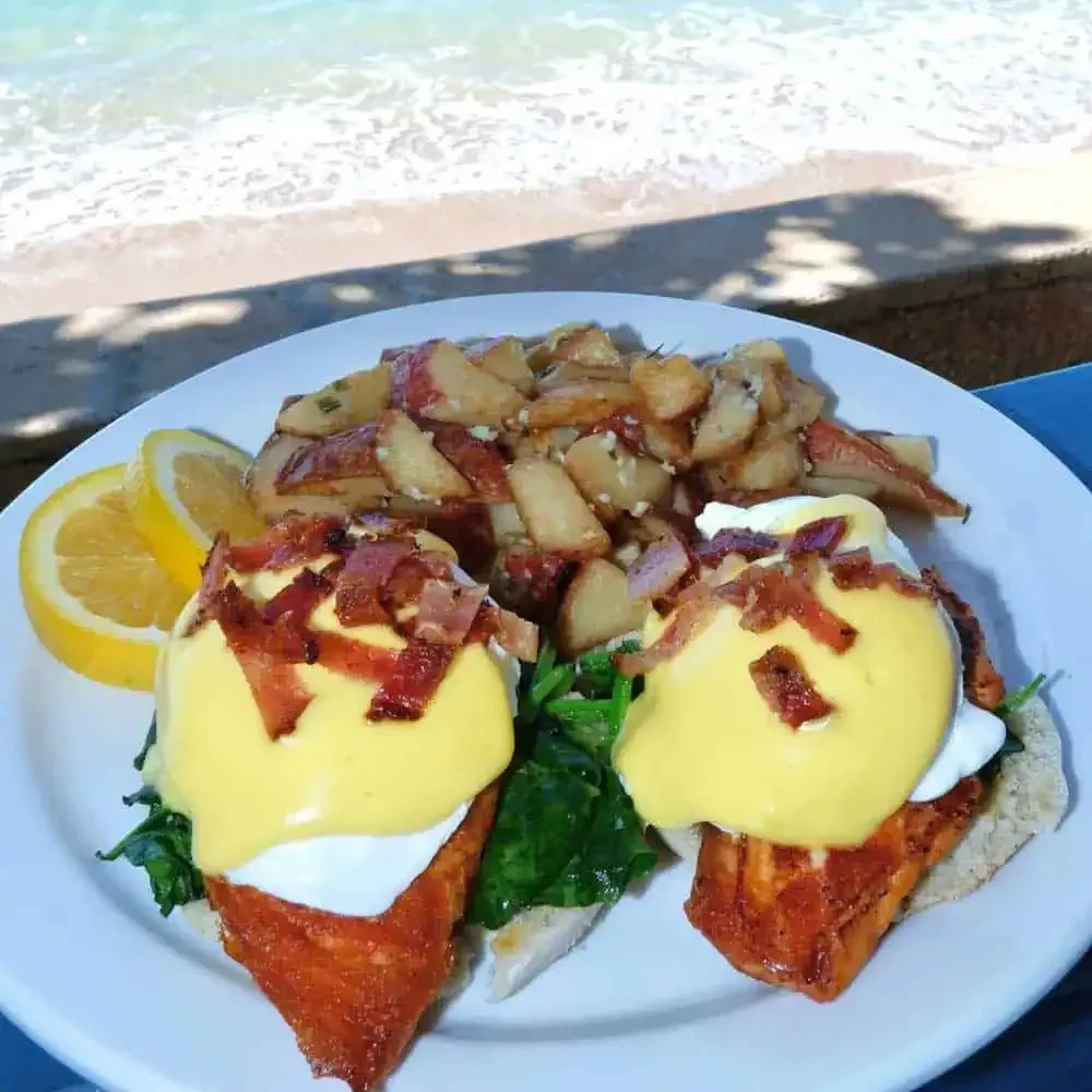 Salmon Eggs Benedict, roasted potatoes, lemon wedges on a beach.