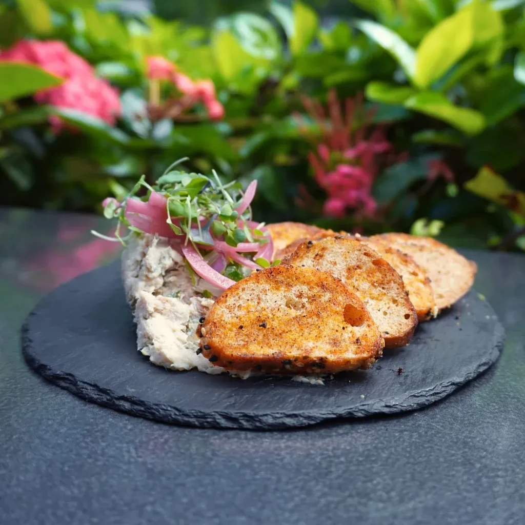 Creamy dip garnished with microgreens, pickled onions, and seasoned toast.