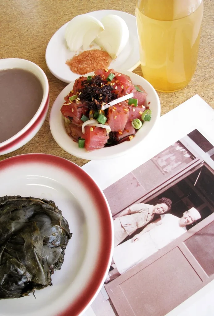 Hawaiian meal with ahi poke, laulau, poi, and a sepia photo.