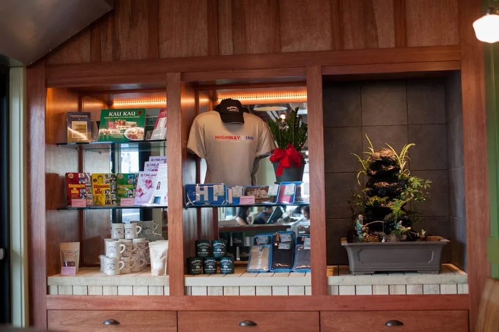 Interior display: books, branded 'HIGHWAY INN' t-shirt, mugs, rock garden.