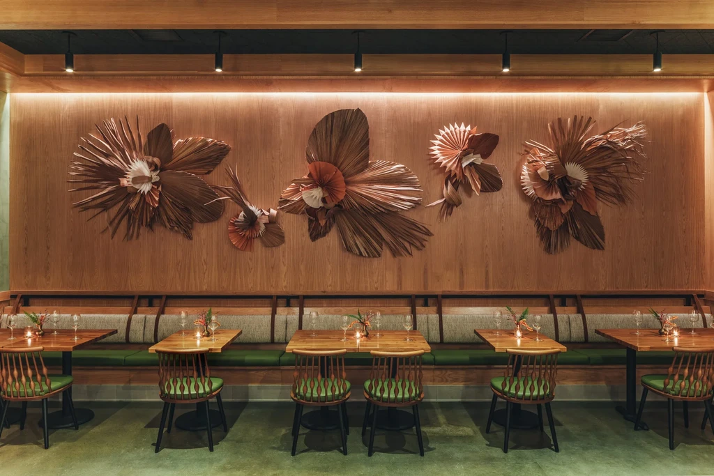 Earth-toned dining area with abstract floral wall art, banquette, and tables.