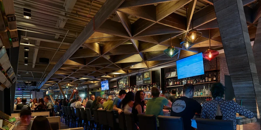 Geometric wooden lattice ceiling highlights this modern, lively bar interior.