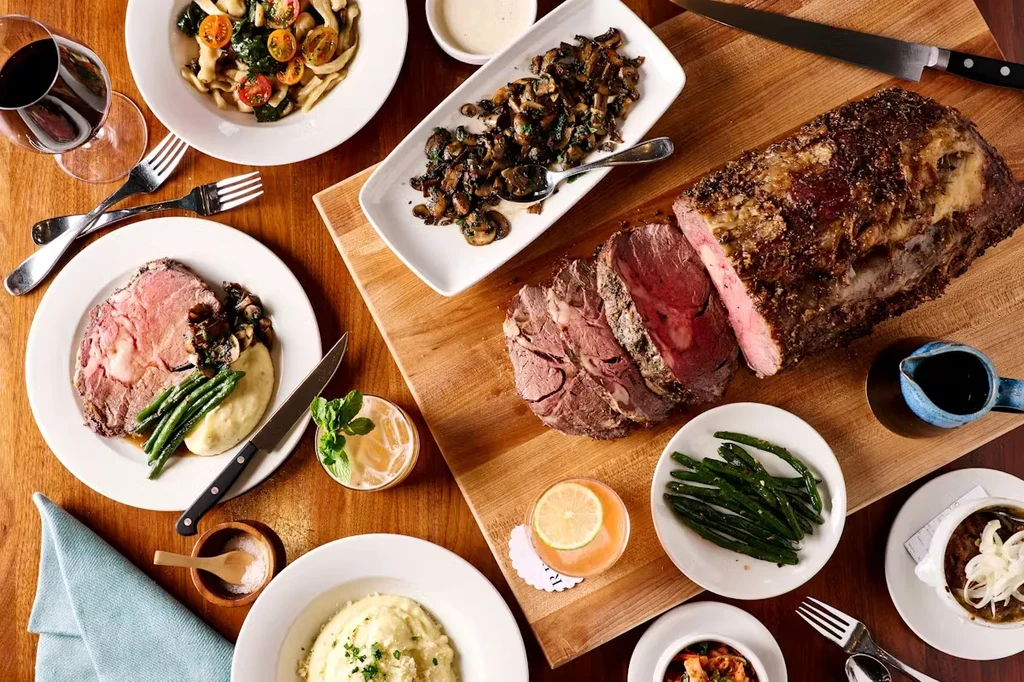 Overhead view of a dining table laden with prime rib and gourmet dishes.