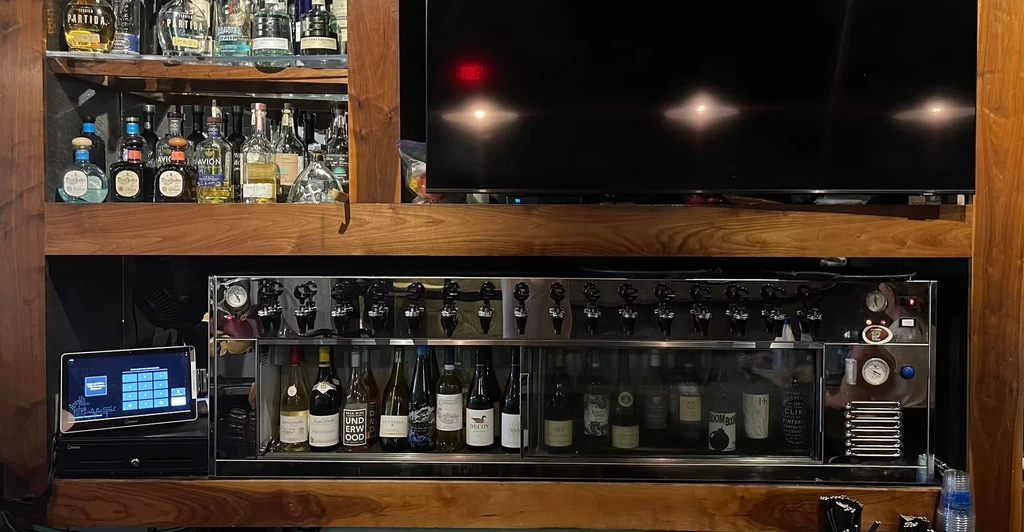 Restaurant bar with liquor shelves, flat-screen TV, multi-tap wine system.