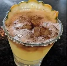Cocktail with frothy foam, marbled liquid, green fruit, sugar rim.