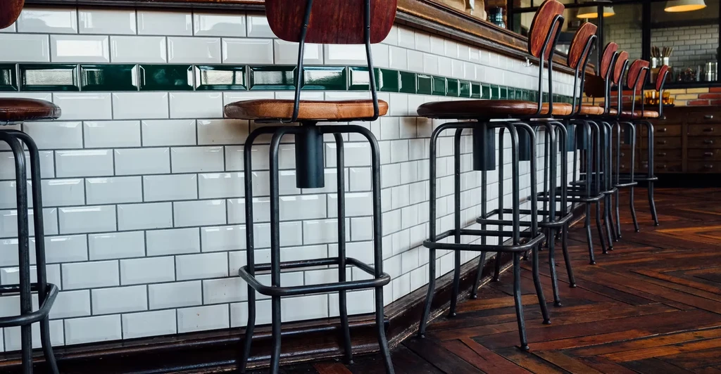 Industrial bar stools at a subway-tiled counter with a herringbone floor.