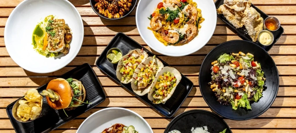 Overhead shot of various food dishes on a slatted wooden table.