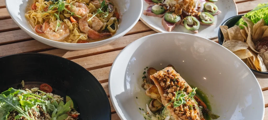 Five vibrant food dishes artfully arranged on a wooden table.