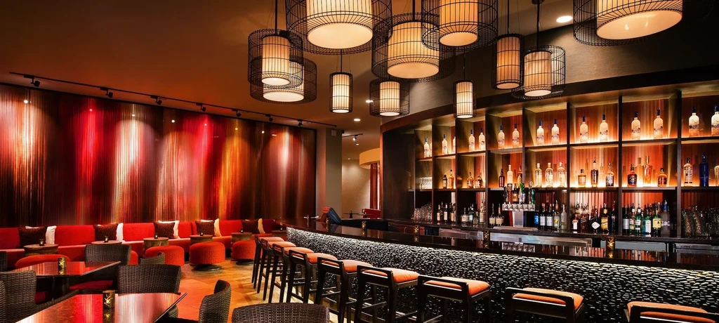 Stylish bar and lounge interior with illuminated bottles and warm decor.