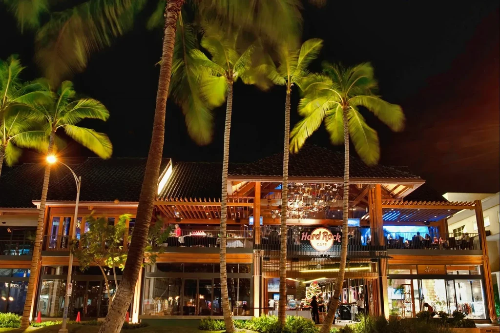 Hard Rock Cafe exterior at night with lit palm trees and diners.