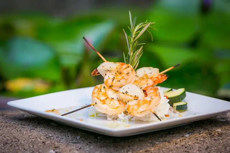 Grilled shrimp and scallop skewers with rice, zucchini, and rosemary.
