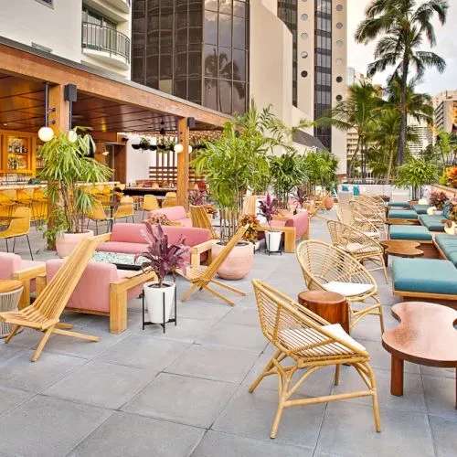 Empty modern restaurant patio with lush plants and diverse seating.