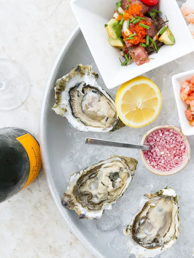 Fresh oysters on ice, poke salad, lemon, and Veuve Clicquot bottle.