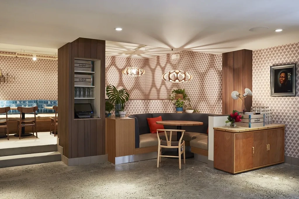 Stylish, empty restaurant interior featuring U-shaped booth, patterned walls, and plants.