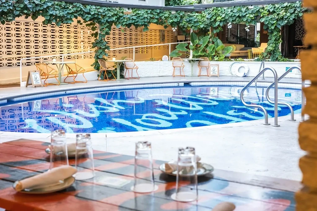 Outdoor resort dining area beside a blue swimming pool, no people.