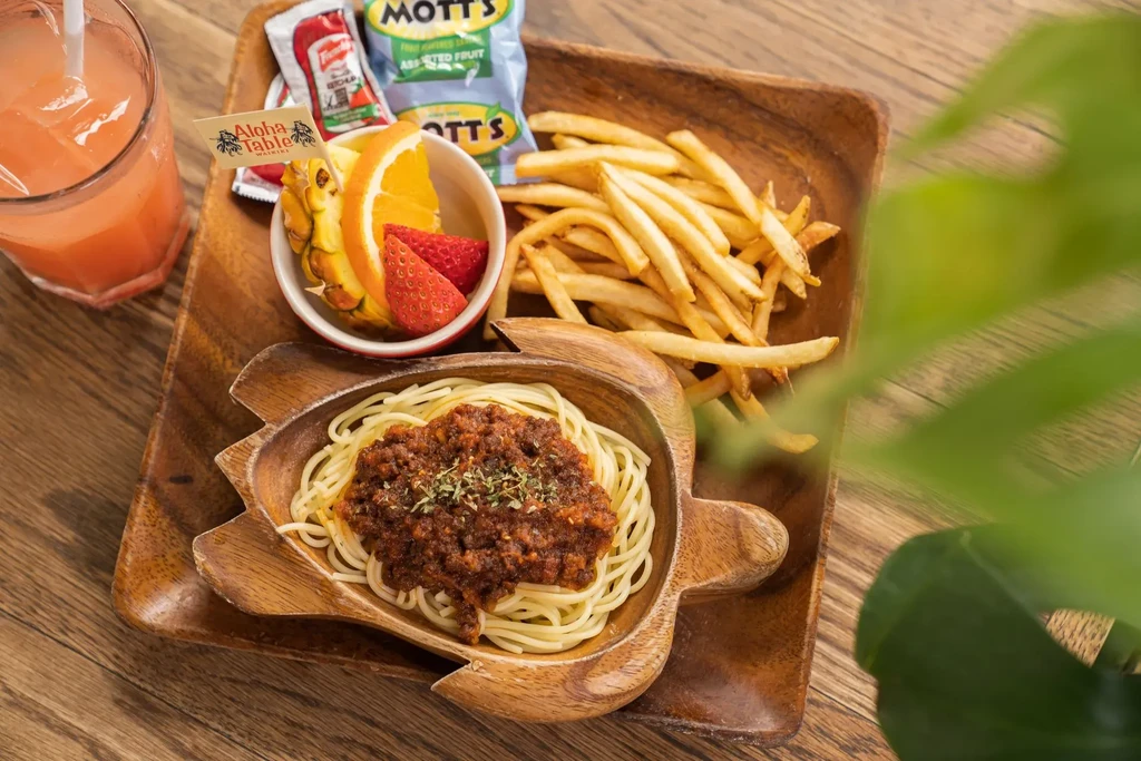 Turtle-shaped spaghetti bolognese, fries, fruit, and pink drink.