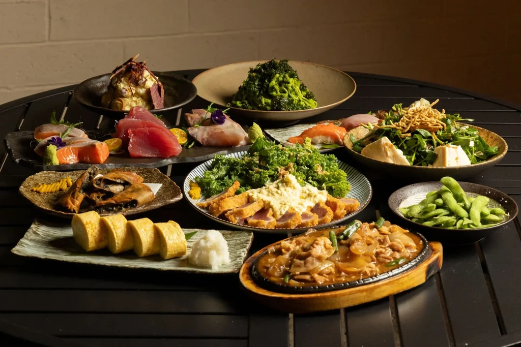 A diverse spread of Japanese dishes: sashimi, tonkatsu, vegetables, and appetizers.