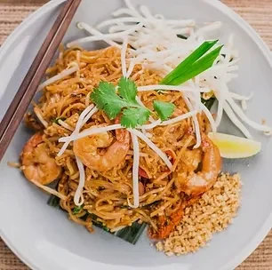 Overhead Pad Thai with shrimp, peanuts, lime, and chopsticks.